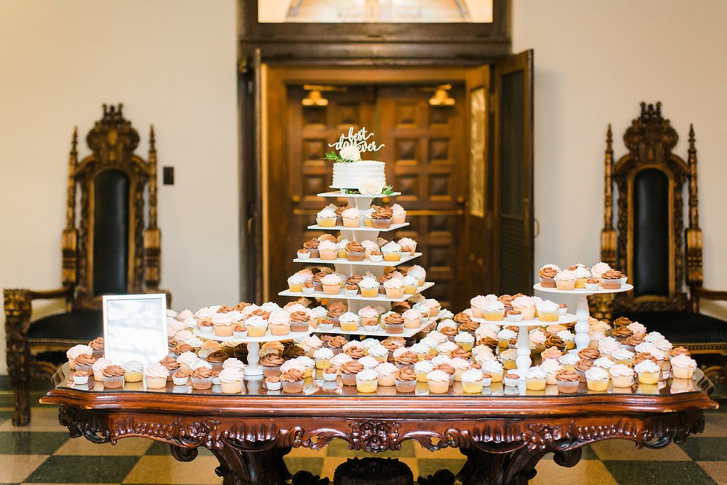 a table with a cupcake tree and various cupcakes from catering wedding vendors