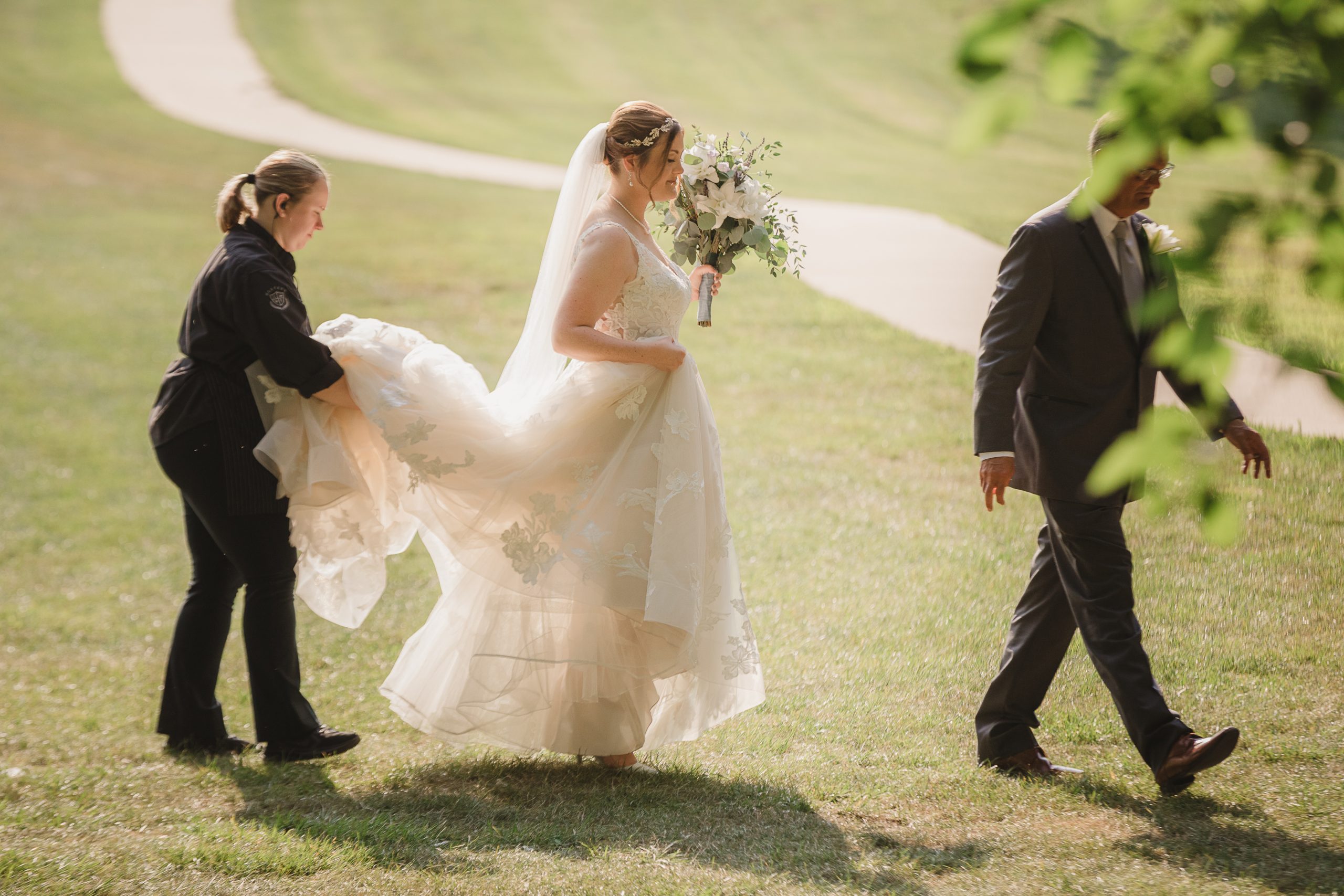 hostess or wedding planner holding a bride's train for her wedding dress 